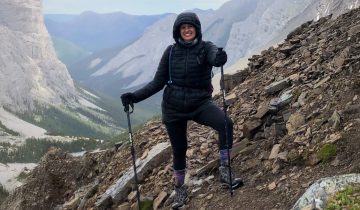 Lacey Smith smiles on a mountain trail in Comox Valley with trekking poles.